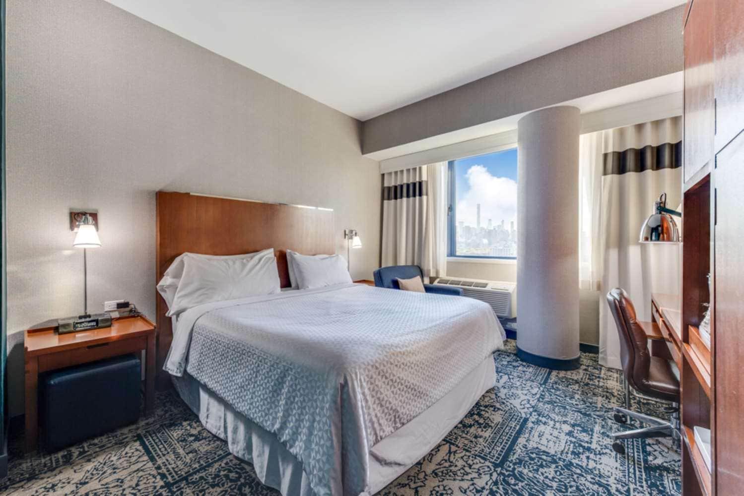 Nichtraucher Suite mit Kingsize-Bett und Blick auf die Stadt.